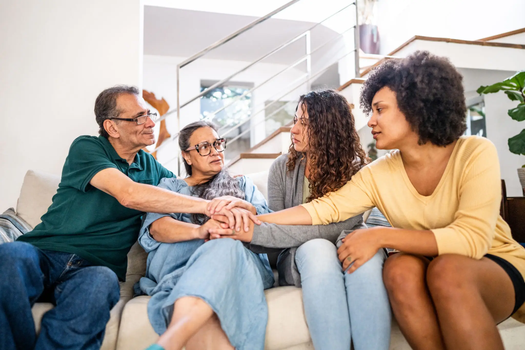 Family holding hands on a couch
