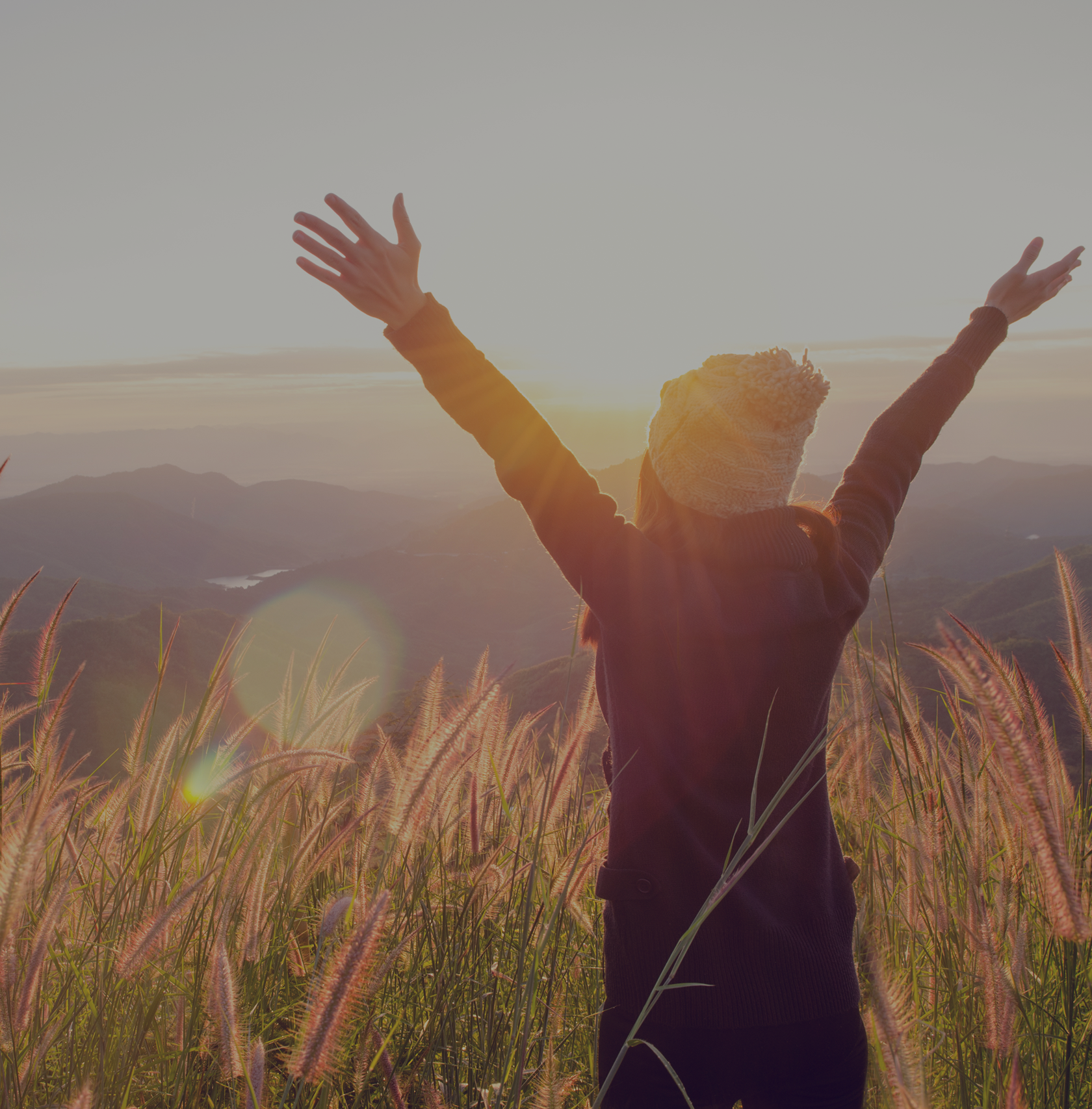 Person celebrating sunrise in grassy field