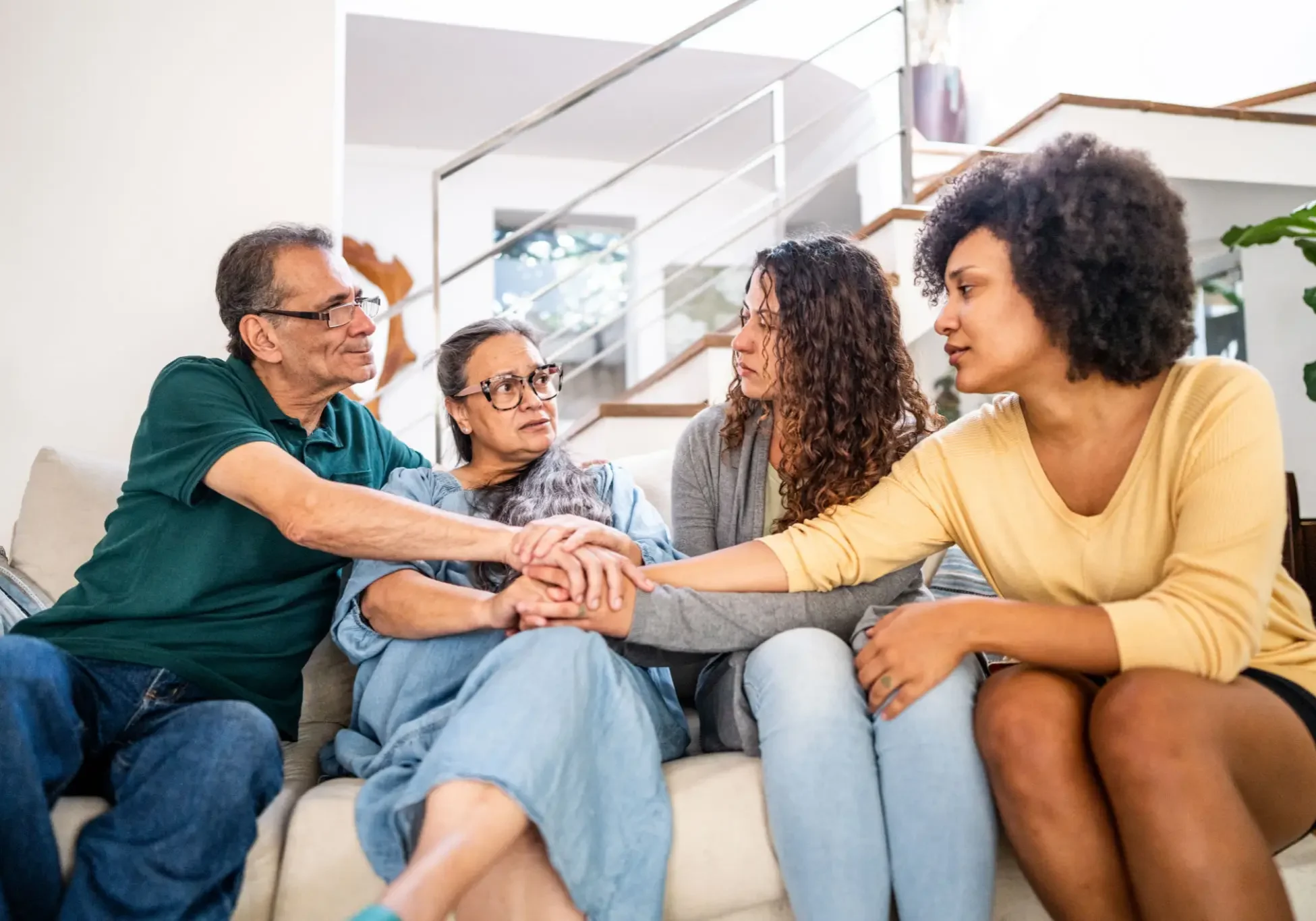 Family holding hands on a couch